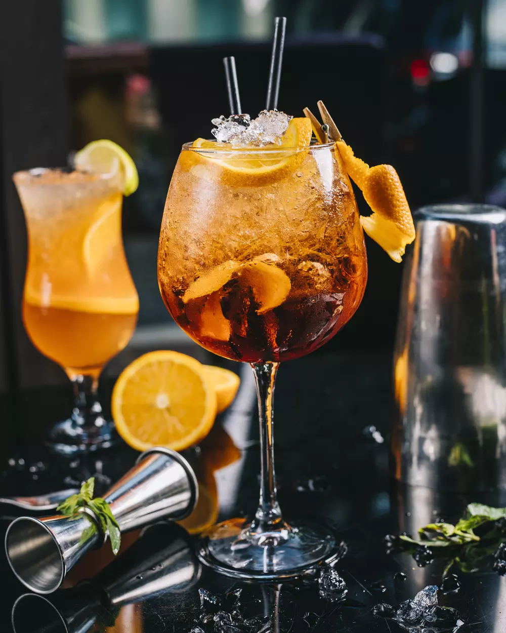 Le barman en train de préparer un cocktail devant un mur de bouteilles de spiritueux.